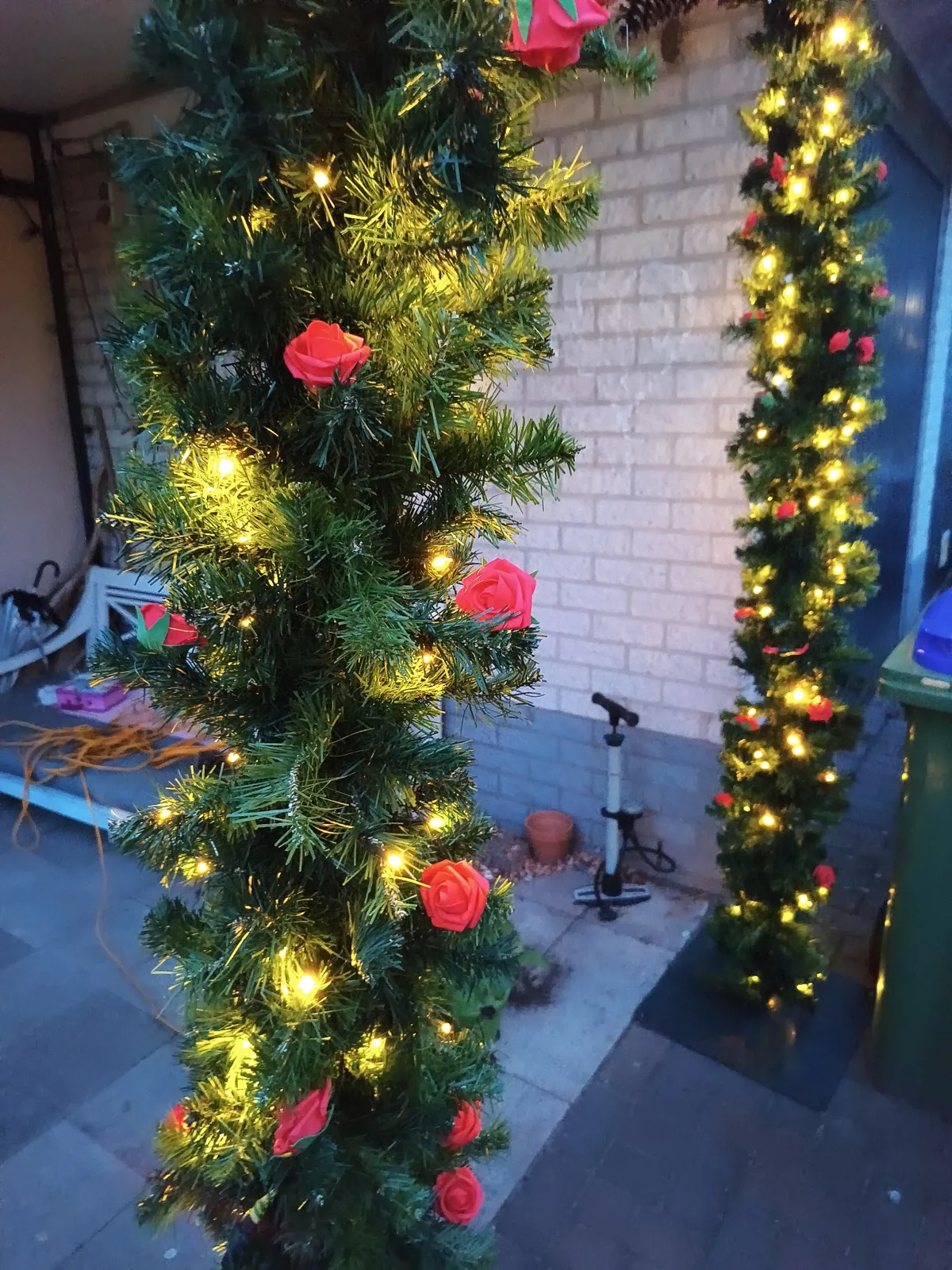 Warme gele lampjes tussen het groen en de rode rozen van de verlichte jubileumboog